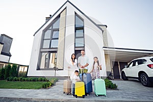 Photo portrait of smiling big full family with small kids outside house with luggage near car keeping bags ready to go