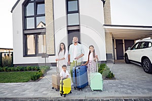 Photo portrait of smiling couple wife husband with small kids keeping suitcases outside home ready for travel