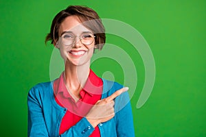 Photo portrait of smiling girl with bob hair pointing with finger at blank space wearing glasses isolated on vibrant