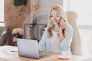 Photo portrait smiling happy business woman wearing glasses sitting at table talking on cellphone