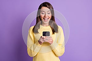 Photo portrait of surprised excited brunette woman holding phone in two hands with open mouth isolated on vivid violet