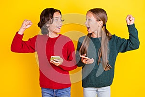 Photo portrait two children keeping mobile phones won virtual game isolated vibrant yellow color background