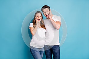 Photo portrait of two people husband pregnant wife touching cheeks amazed isolated on bright blue color background