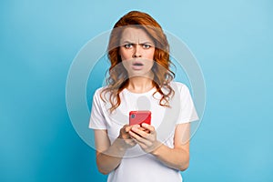 Photo portrait of unhappy girl holding phone in two hands isolated on pastel blue colored background