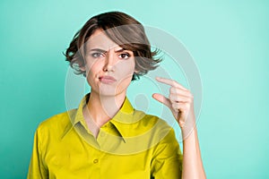 Photo portrait of unhappy girl showing small size fingers isolated on bright turquoise color background