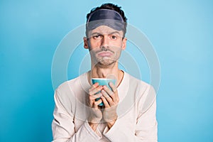 Photo portrait of upset tired guy holding tea cup in two hands isolated on vivid blue colored background