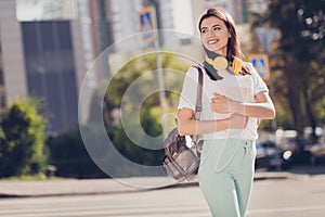 Photo portrait of woman crossing street holding white book looking to side outdoors