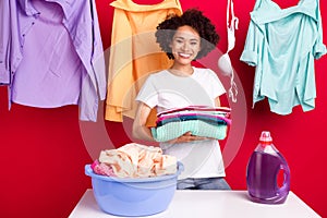 Photo portrait woman happy keeping clean clothes at home isolated vibrant red color background