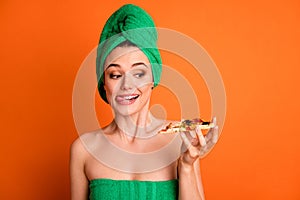 Photo portrait of woman holding in one hand looking at pizza slice licking lips isolated on vivid orange colored