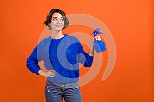 Photo portrait woman keeping pulverizer watering plants looking empty space isolated orange color background copyspace