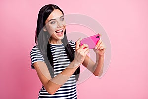 Photo portrait of woman playing video games holding phone in two hands vertically isolated on pastel pink colored