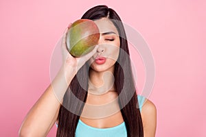 Photo portrait woman sending air kiss keeping exotic fruit covered face eye isolated pastel pink color background