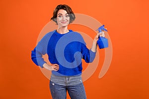 Photo portrait woman smiling keeping pulverizer watering plants isolated orange color background copyspace