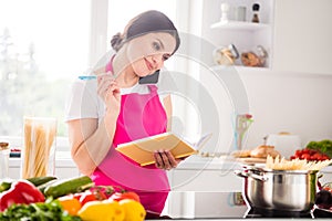 Photo portrait woman writing recipe in blocknote cooking pasta talking on smartphone