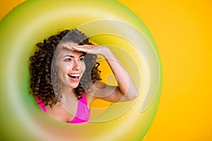 Photo portrait of young girl looking in distance hand at forehead inside inflatable green ring wearing fuchsia swim wear