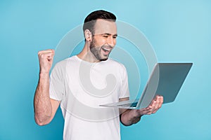 Photo of positive astonished man fist up open mouth celebrate look laptop isolated on blue color background