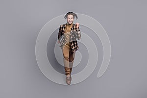 Photo of positive attractive guy dressed checkered shirt jumping high running fast isolated grey color background