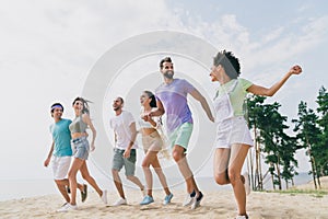 Photo of positive carefree people hold hands walk running beach coast free time hang out outside