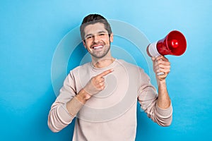 Photo of positive cheerful guy dressed beige sweatshirt showing finger loud speaker isolated blue color background