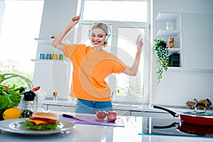 Photo of positive cheerful lady cooking dish meal with fresh tomato dance with energetic melody headset in kitchen