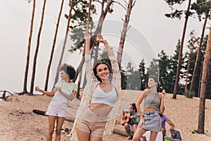 Photo of positive cheerful people enjoy free time hanging out dancing beach outside