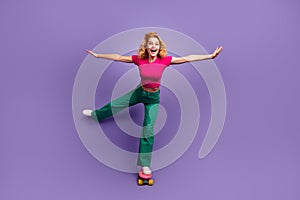 Photo of positive cheerful woman wear trendy pink clothes riding pennyboard isolated on purple color background