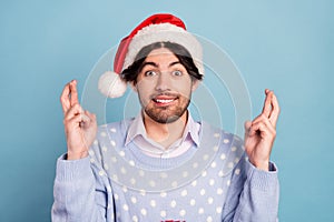 Photo of positive cheerful young man hold fingers crossed expect present isolated on blue color background