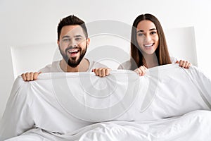 Photo of positive couple girl guy hold white blanket bed in morning room