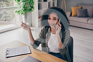 Photo of positive excited lady entrepreneur dressed shirt communicating modern gadget writing clipboard indoors workshop