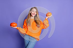 Photo of positive excited nice girl toothy smile hands hold pumpkins empty space ad isolated on violet color background