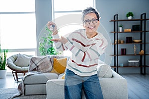 Photo of positive friendly grandmother hand hold demonstrate new house key spacious interior indoors