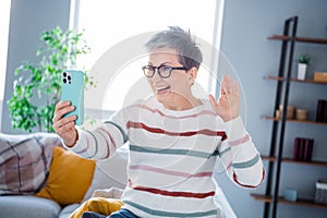 Photo of positive friendly lady wear striped pullover spectacles waving hi video call modern device indoors room home