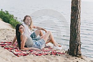 Photo of positive funny young couple dressed casual outfits sunbathing beach outdoors countryside