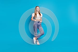 Photo of positive girl look empty space hand sin pockets jeans isolated blue color background