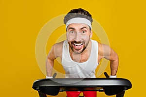 Photo of positive good mood guy activewear walking treadmill hurrying shopping empty space isolated yellow color