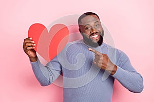 Photo of positive guy direct finger heart symbol toothy smile wear grey shirt isolated pink color background photo