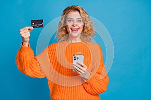 Photo of positive nice pretty woman wear stylish orange clothes hold bank credit card transfer transaction isolated on