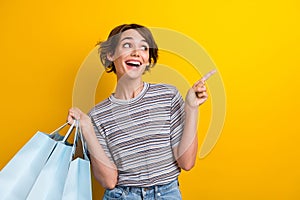 Photo of positive pretty girl dressed trendy clothes presenting empy space cool proposition isolated on yellow color