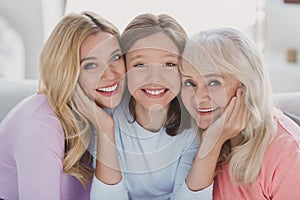 Photo of positive small girl woman and grandmother daughter hold hands cheeks smile indoors inside house