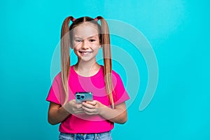 Photo of positive sweet girl toothy smile hands hold smart phone empty space isolated on teal color background