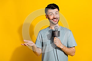 Photo of positive talented man announcer speak mic tell breaking true news empty space isolated on yellow color