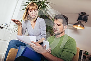 Positive young couple embracing and calculating the bills at home