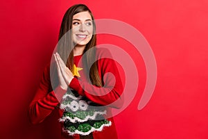 Photo of positive young dreamy woman smile good mood hold hands anticipate isolated on red color background