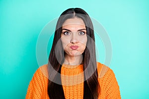 Photo of positive young lady inflate cheeks look camera have fun wear orange sweater  teal color background