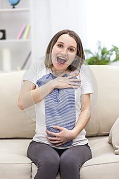 Photo of pregnant woman wearing casual clothes and holding childish clothes in hands.