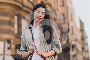 Photo of pretty adorable young asian woman wear khaki shirt enjoying summer sunshine walking city tour outside urban