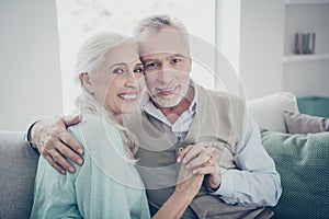 Photo of pretty aged pair leaning heads holding hands posing family portrait sitting cozy sofa indoors