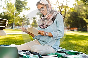Photo of pretty arabic woman wearing headscarf reading books