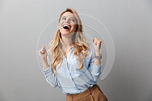 Photo of pretty blond businesswoman with long curly hair laughing and clenching her fists