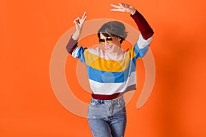 Photo of pretty carefree girl look empty space two hands fingers show v-sign isolated on orange color background